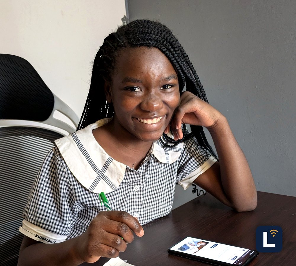 A Lory Online School student smiling, holding up their phone showing the Learning Portal